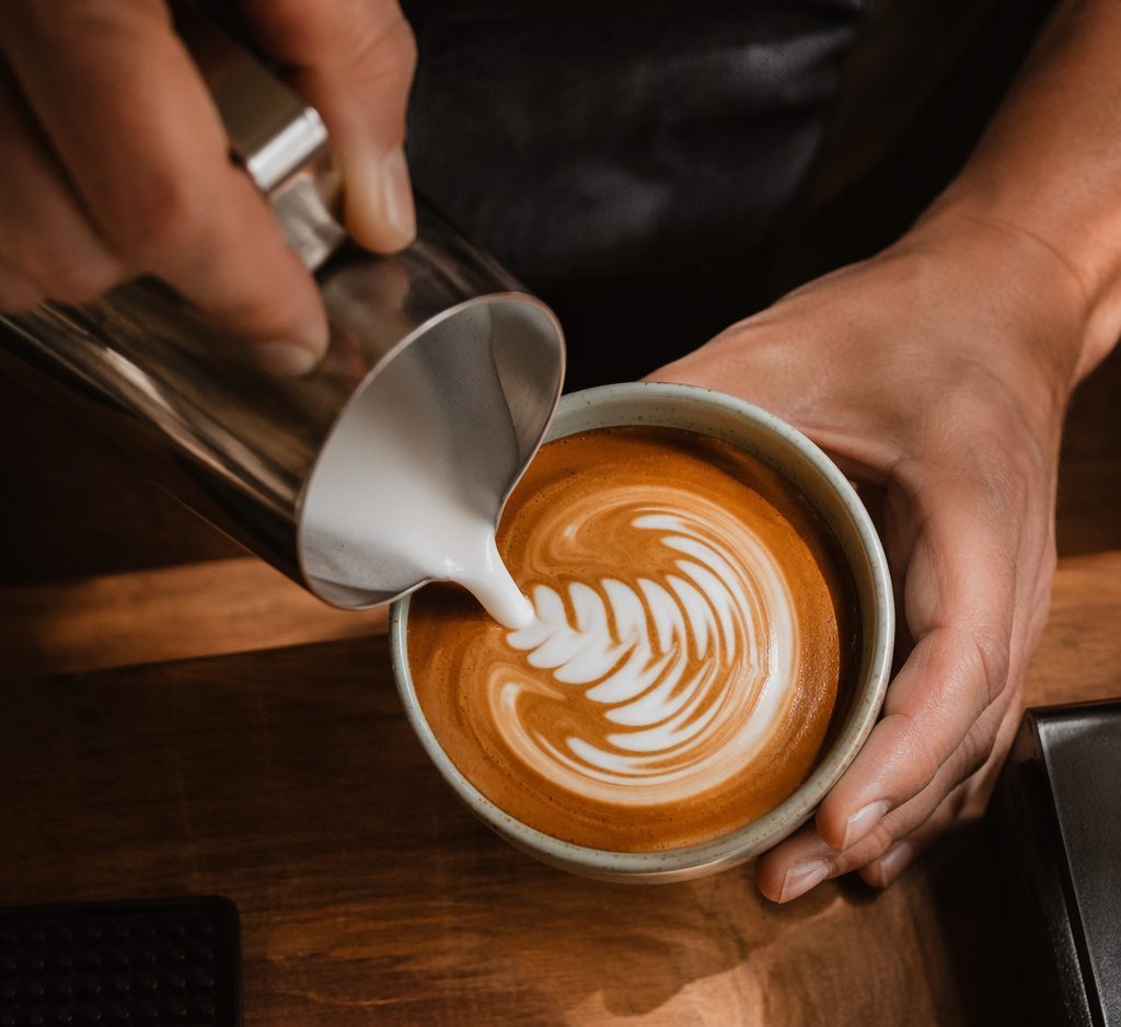 Overhead shot of rosetta latte art being poured into a hand-thrown ceramic cup